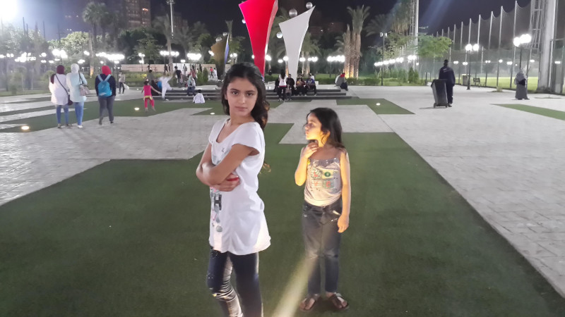 Two children in t-shirts and jeans in an open space in Gaza, before the genocide