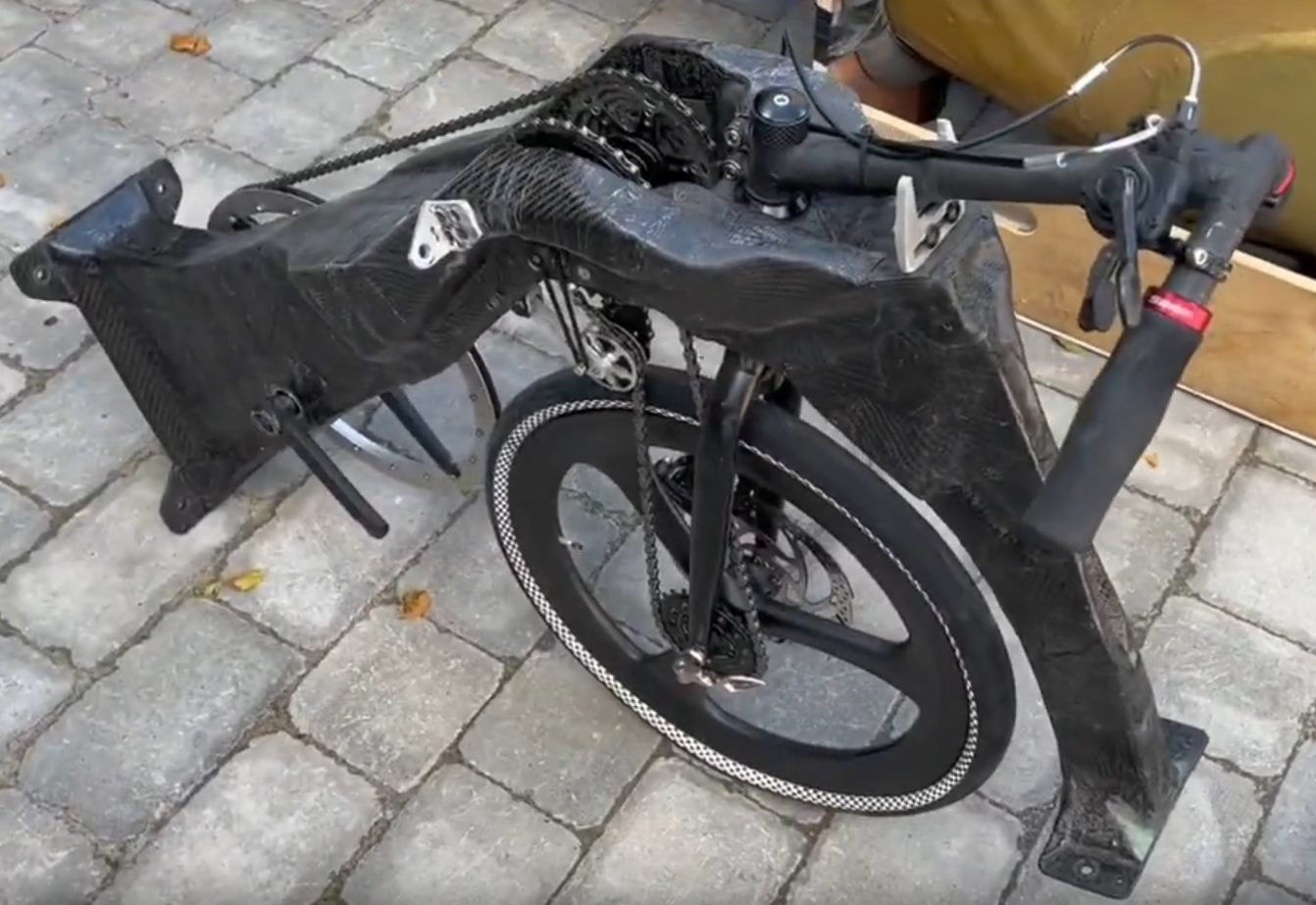 A largely carbon fibre subframe, carrying a bicycle transmission and steerable front wheel, with an extremely large chainring but relatively small wheel.